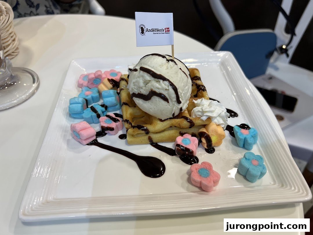 A delicious waffle topped with vanilla ice cream, chocolate sauce, whipped cream, and flower-shaped marshmallows.