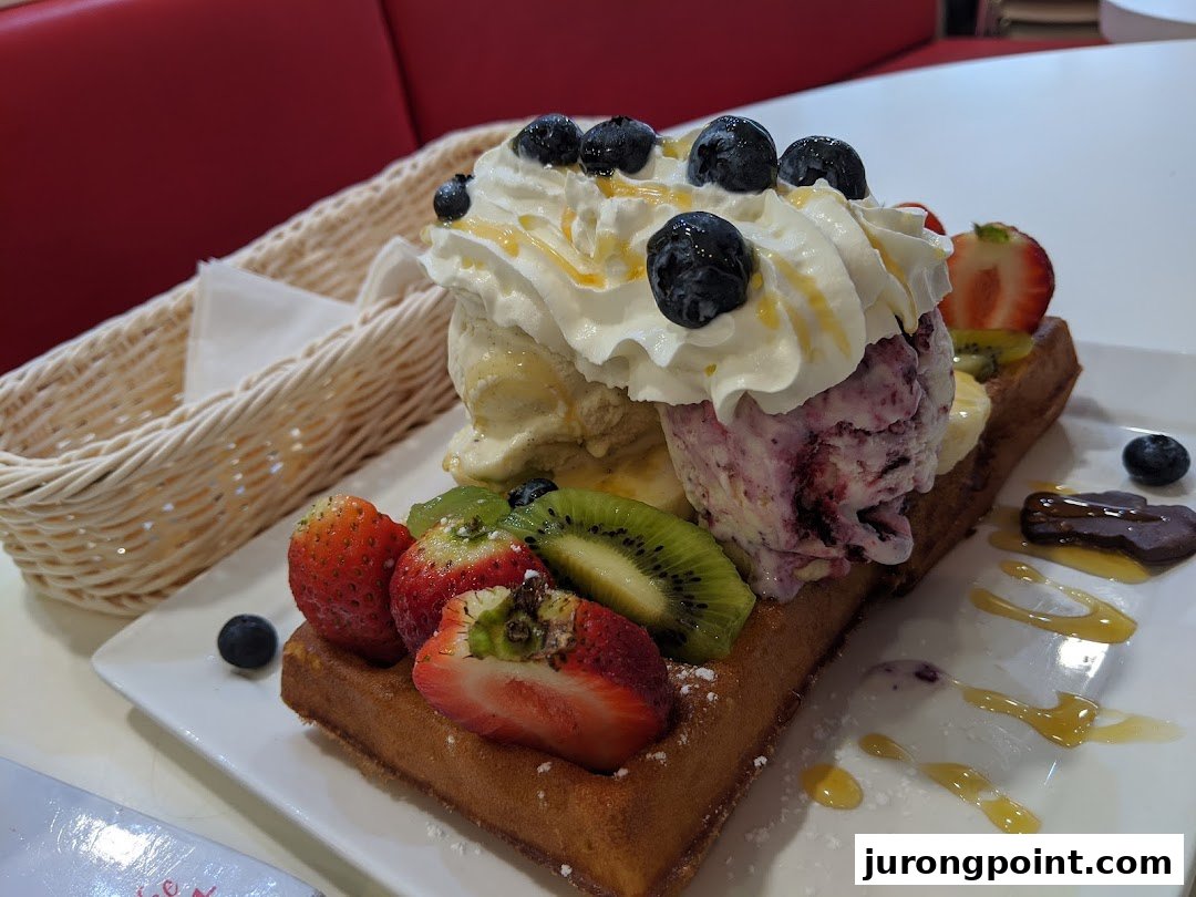 A delectable waffle topped with ice cream, whipped cream, fresh berries, kiwi, and a drizzle of honey.