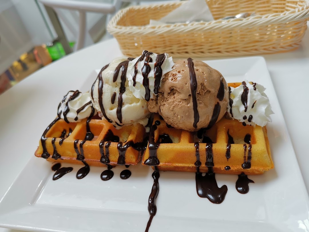 Delicious waffles topped with vanilla and chocolate ice cream, whipped cream, and chocolate drizzle.