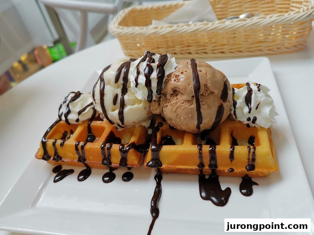 Delicious waffles topped with vanilla and chocolate ice cream, whipped cream, and chocolate drizzle.