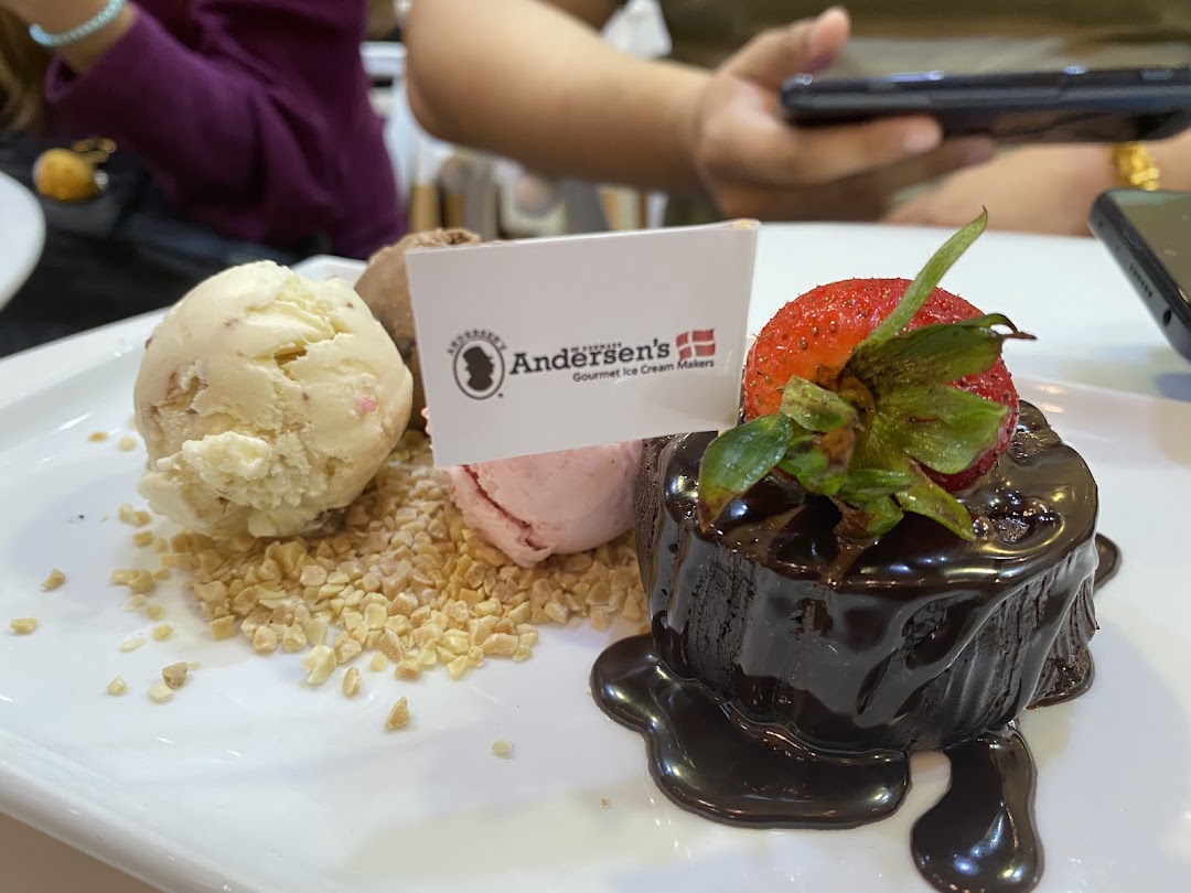 A delicious dessert featuring ice cream scoops, chopped nuts, and a chocolate lava cake with a strawberry.