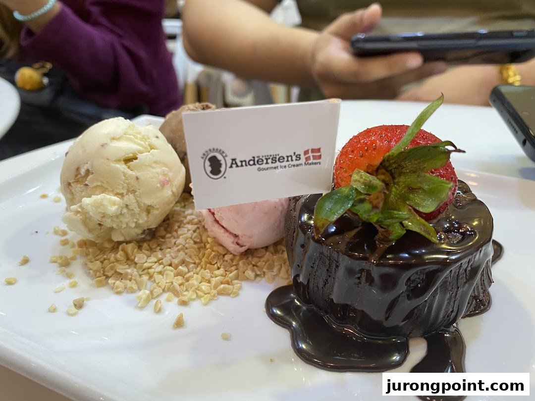 A delicious dessert featuring ice cream scoops, chopped nuts, and a chocolate lava cake with a strawberry.