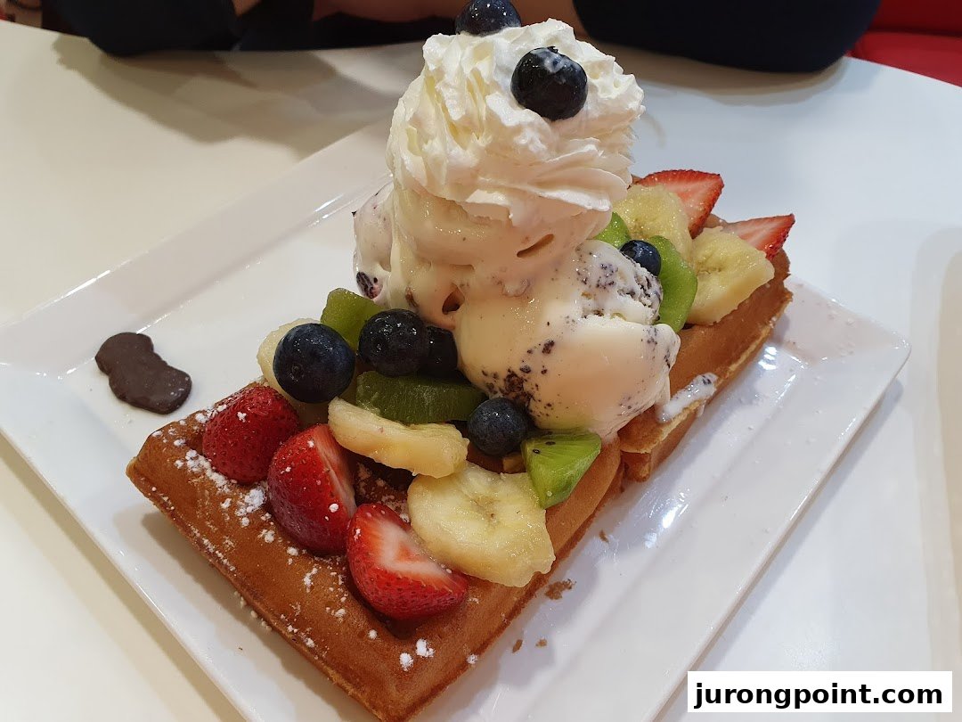 A delicious waffle topped with ice cream, whipped cream, and fresh mixed berries and fruit.