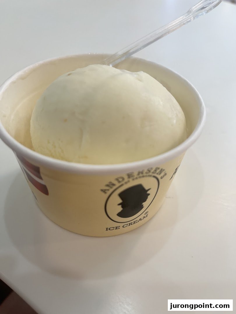 A single scoop of creamy ice cream in an Andersens of Denmark branded cup with a clear spoon.