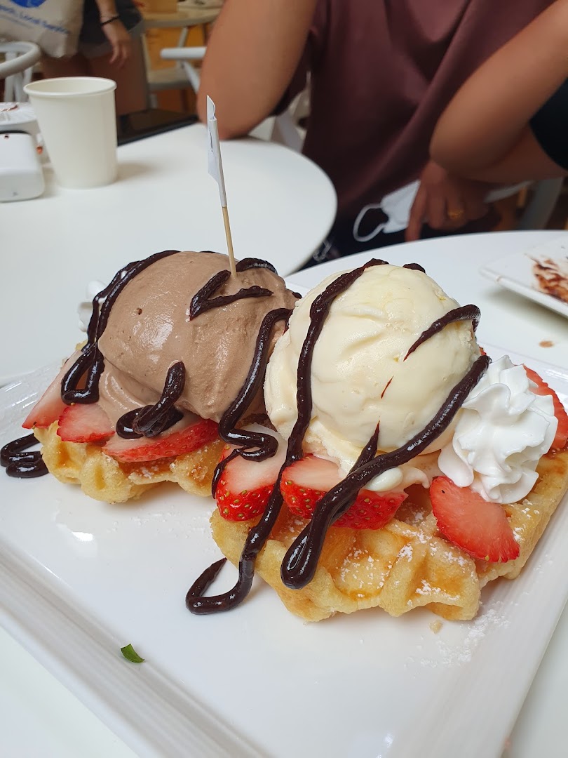 Two delicious waffles topped with strawberries, chocolate and vanilla ice cream, and chocolate sauce.