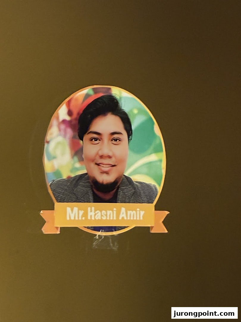 A circular photo of Mr. Hasni Amir, likely an instructor at Aureus Academy.