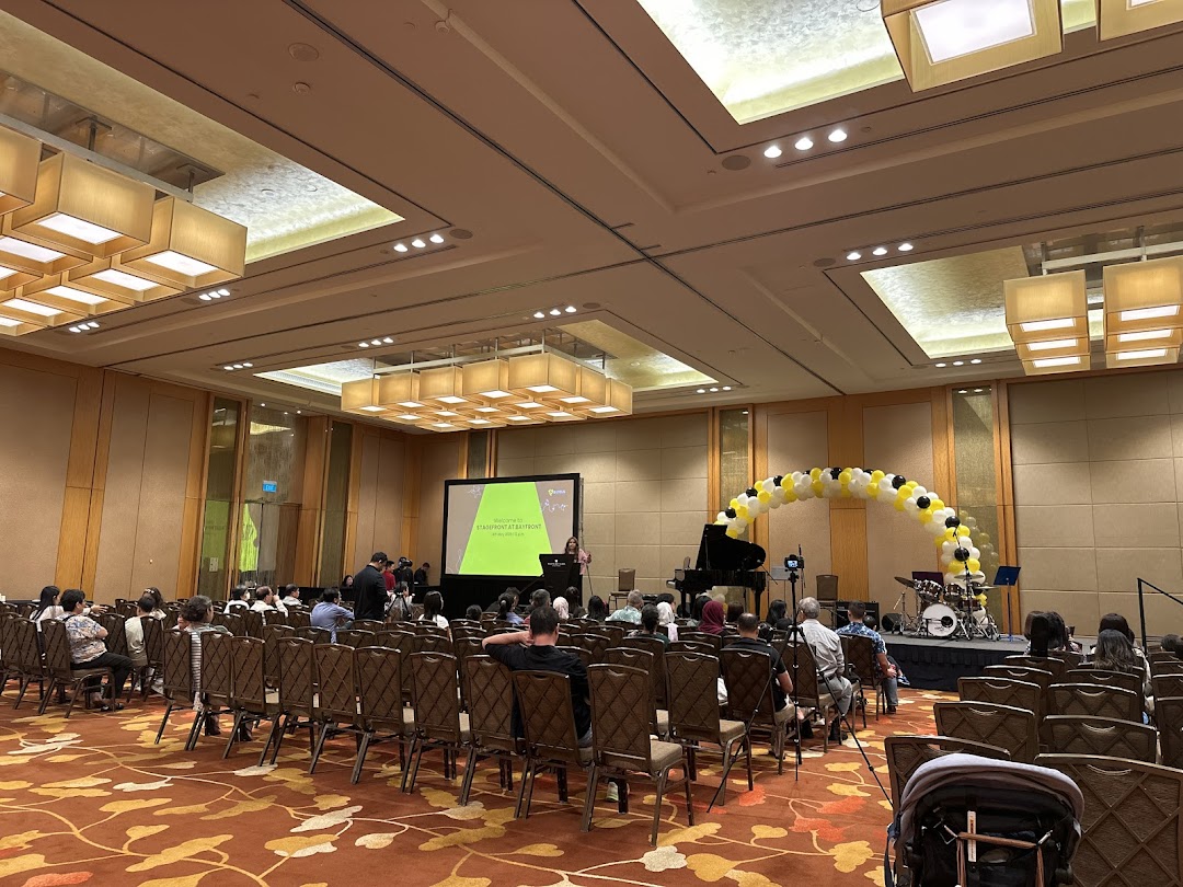Audience gathered for a musical performance or presentation by Aureus Academy in a large hall.