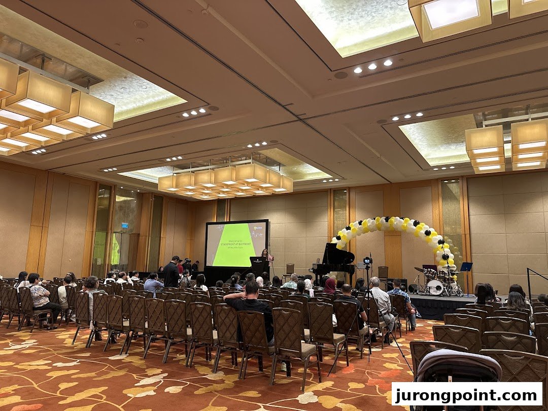 Audience gathered for a musical performance or presentation by Aureus Academy in a large hall.