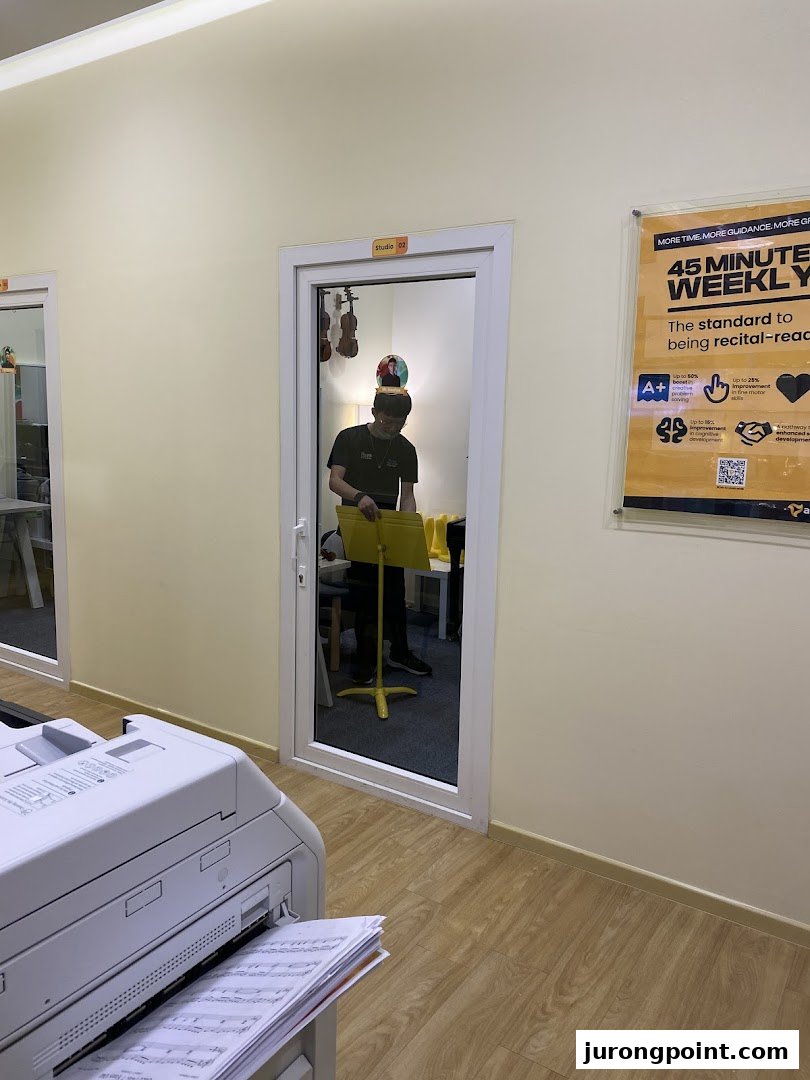 Interior view of Aureus Academy, showing a music studio door and a promotional poster.
