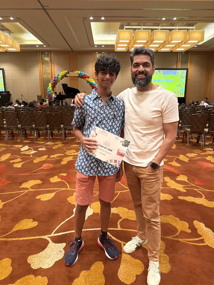 A student and adult proudly display a certificate at an Aureus Academy music event.
