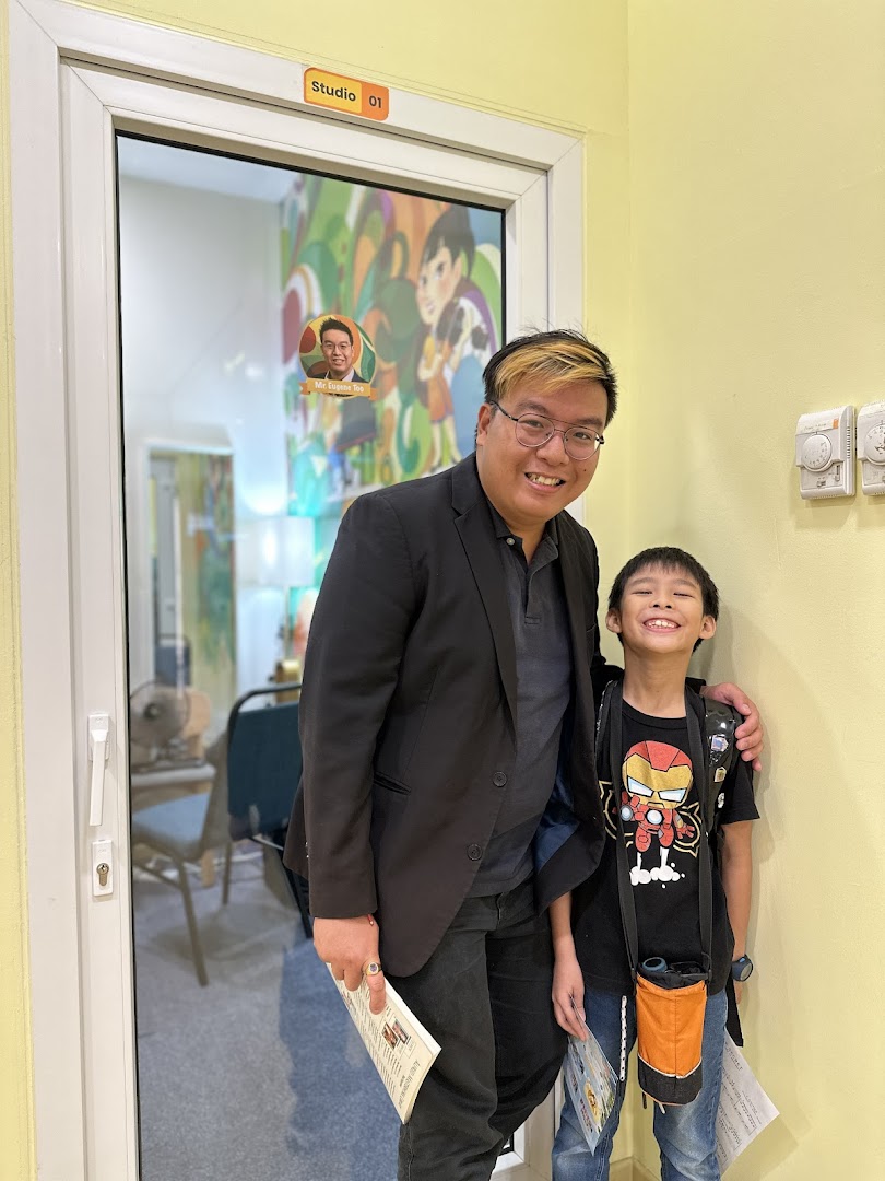 An adult and a child smiling in front of "Studio 01" at Aureus Academy.