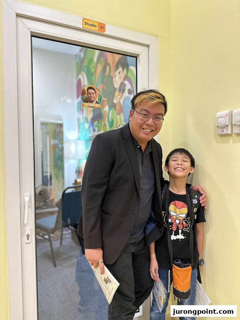 An adult and a child smiling in front of "Studio 01" at Aureus Academy.