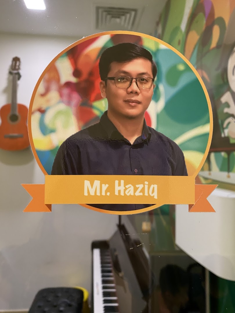 A cutout of Mr. Haziq, a music instructor, with a piano and guitar in the background.