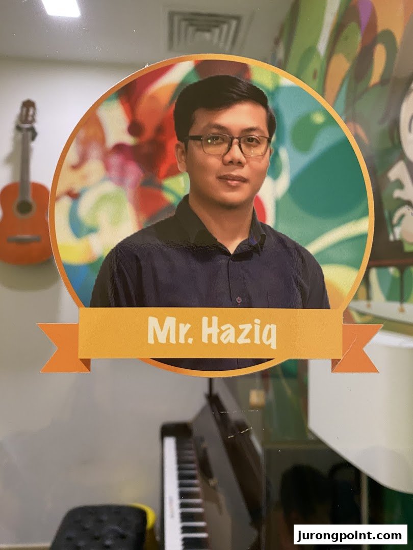 A cutout of Mr. Haziq, a music instructor, with a piano and guitar in the background.