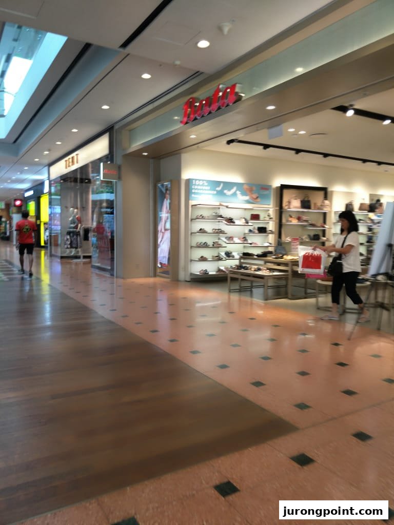 View of the Bata shoe store interior from the mall corridor with a shopper inside.