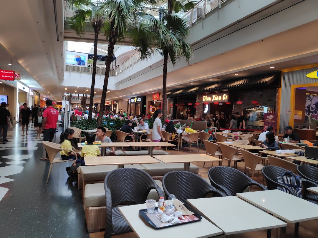 A bustling mall interior featuring a spacious dining area, lush palm trees, and various eateries.