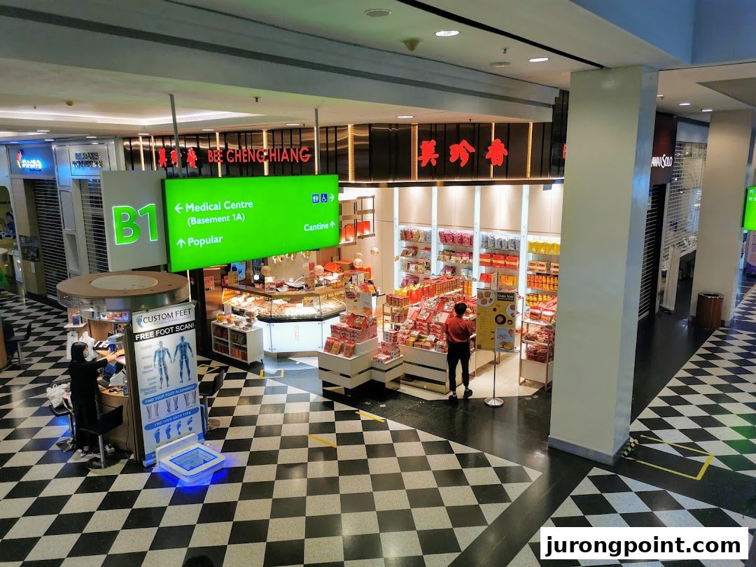 A bustling Bee Cheng Hiang shop in a mall, showcasing its products, with a 'Custom Feet' booth nearby.