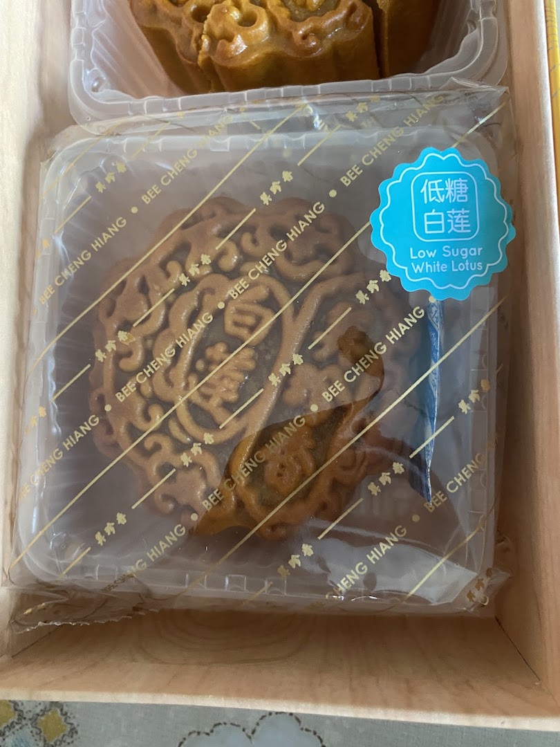 A Bee Cheng Hiang low sugar white lotus mooncake in its individual packaging, part of a gift box.