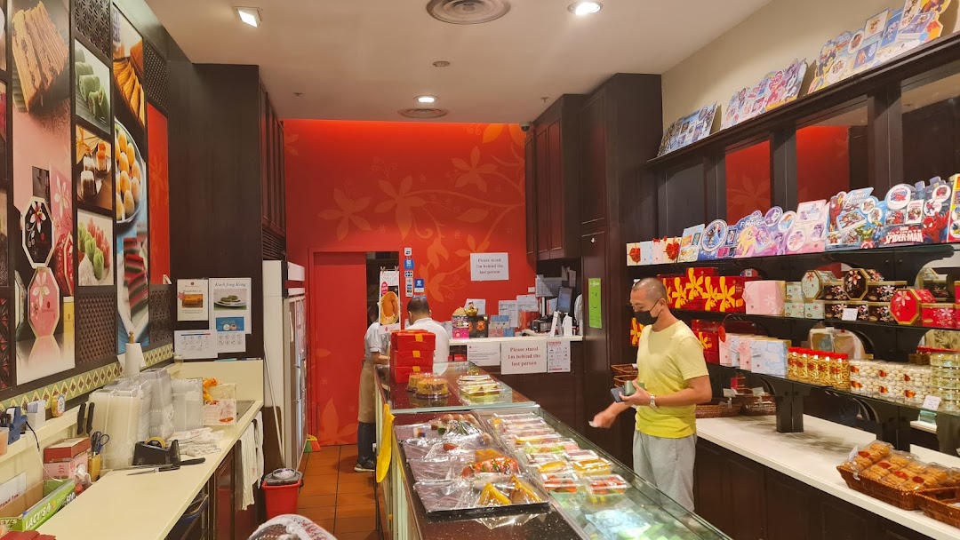 Interior view of Bengawan Solo bakery, showcasing traditional cakes, pastries, and gift items with customers browsing.
