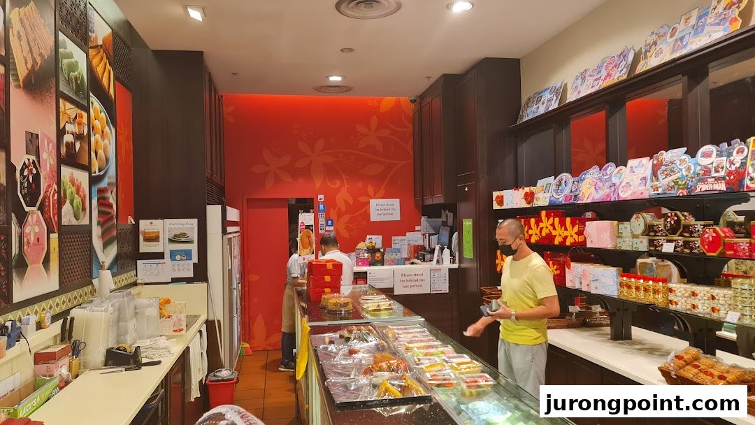 Interior view of Bengawan Solo bakery, showcasing traditional cakes, pastries, and gift items with customers browsing.