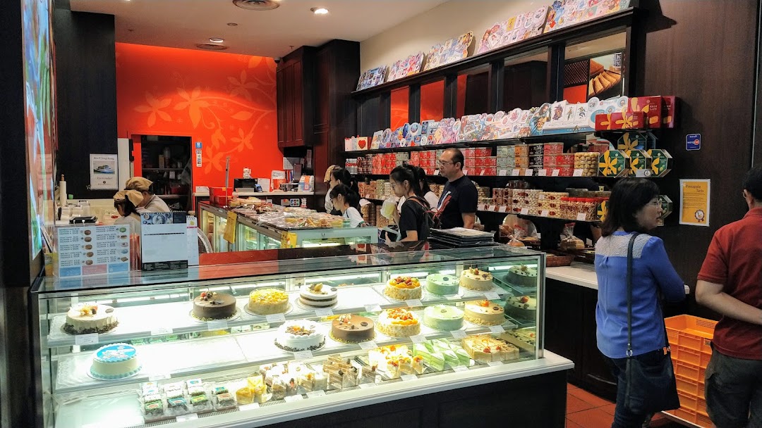 An interior view of Bengawan Solo bakery, showcasing a display of cakes, pastries, and customers.