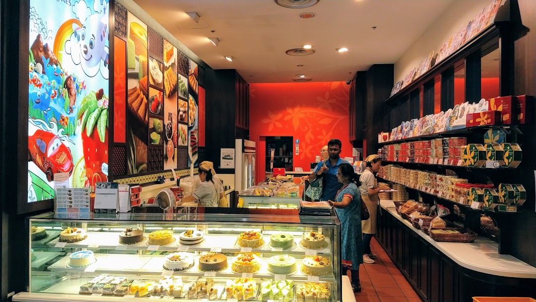Interior view of Bengawan Solo bakery, showcasing cakes, pastries, and packaged goods with staff assisting customers.
