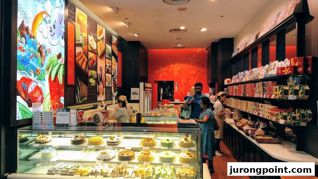 Interior view of Bengawan Solo bakery, showcasing cakes, pastries, and packaged goods with staff assisting customers.