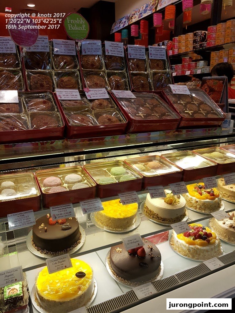 A vibrant display of freshly baked mooncakes, snowskin pastries, and delicious cakes in a retail shop.