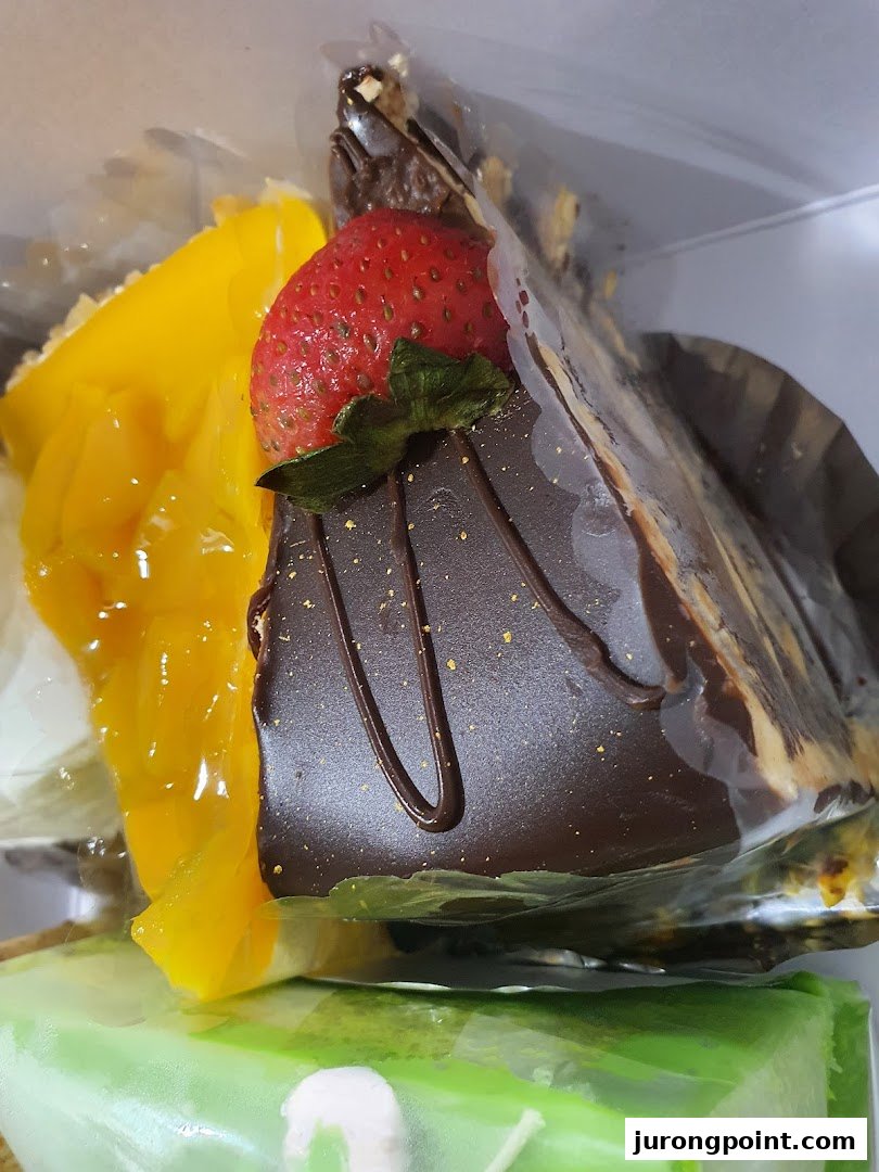 Close-up of delicious cakes, including chocolate with strawberry and a vibrant yellow fruit cake.