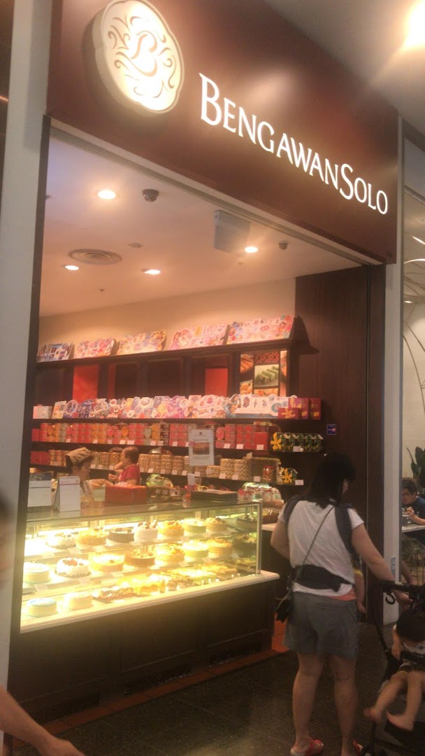 A vibrant shop front of Bengawan Solo, showcasing a display of cakes and pastries, with customers entering.