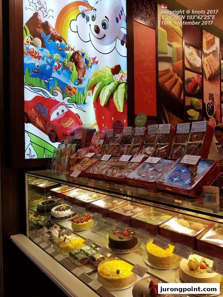 A vibrant display of traditional Indonesian cakes, pastries, and packaged treats inside a Bengawan Solo shop.