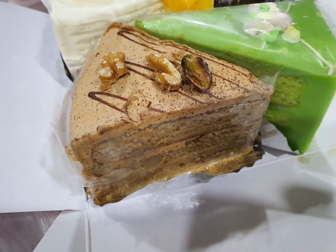 Close-up of delicious layered cakes, including a coffee-flavored slice with walnuts and a green pandan cake.