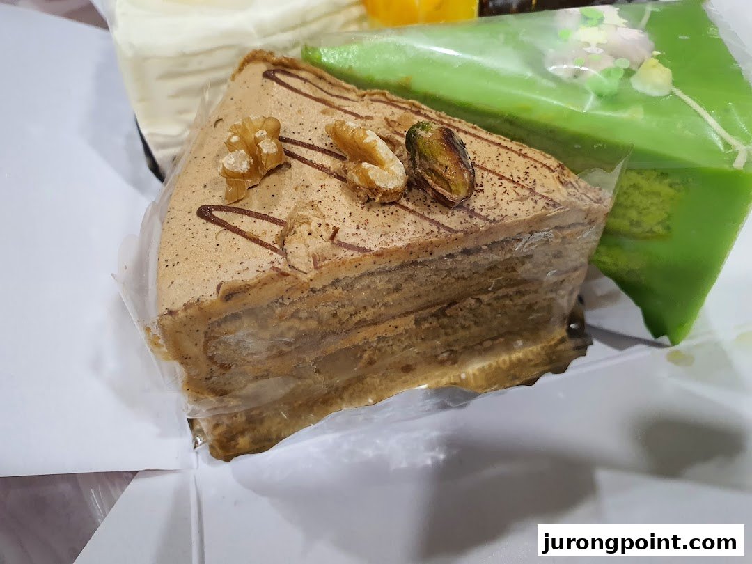 Close-up of delicious layered cakes, including a coffee-flavored slice with walnuts and a green pandan cake.