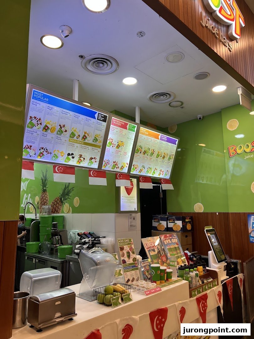 Interior view of Boost Juice featuring prominent digital menu boards displaying various juice and smoothie options.