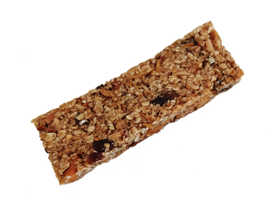 A close-up shot of a healthy granola bar, packed with oats, nuts, and dried fruit.