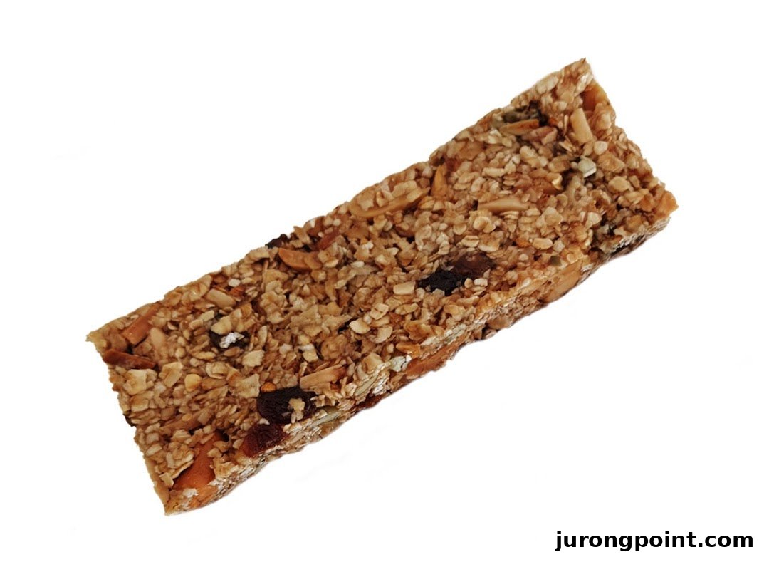 A close-up shot of a healthy granola bar, packed with oats, nuts, and dried fruit.