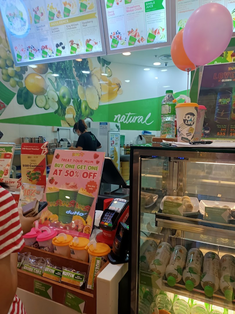 Interior view of a Boost Juice bar, showcasing menu boards, fresh produce, and a staff member.