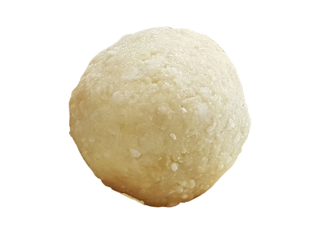 A close-up of a single, light-colored, spherical energy bite or bliss ball.