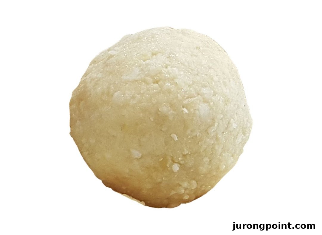 A close-up of a single, light-colored, spherical energy bite or bliss ball.