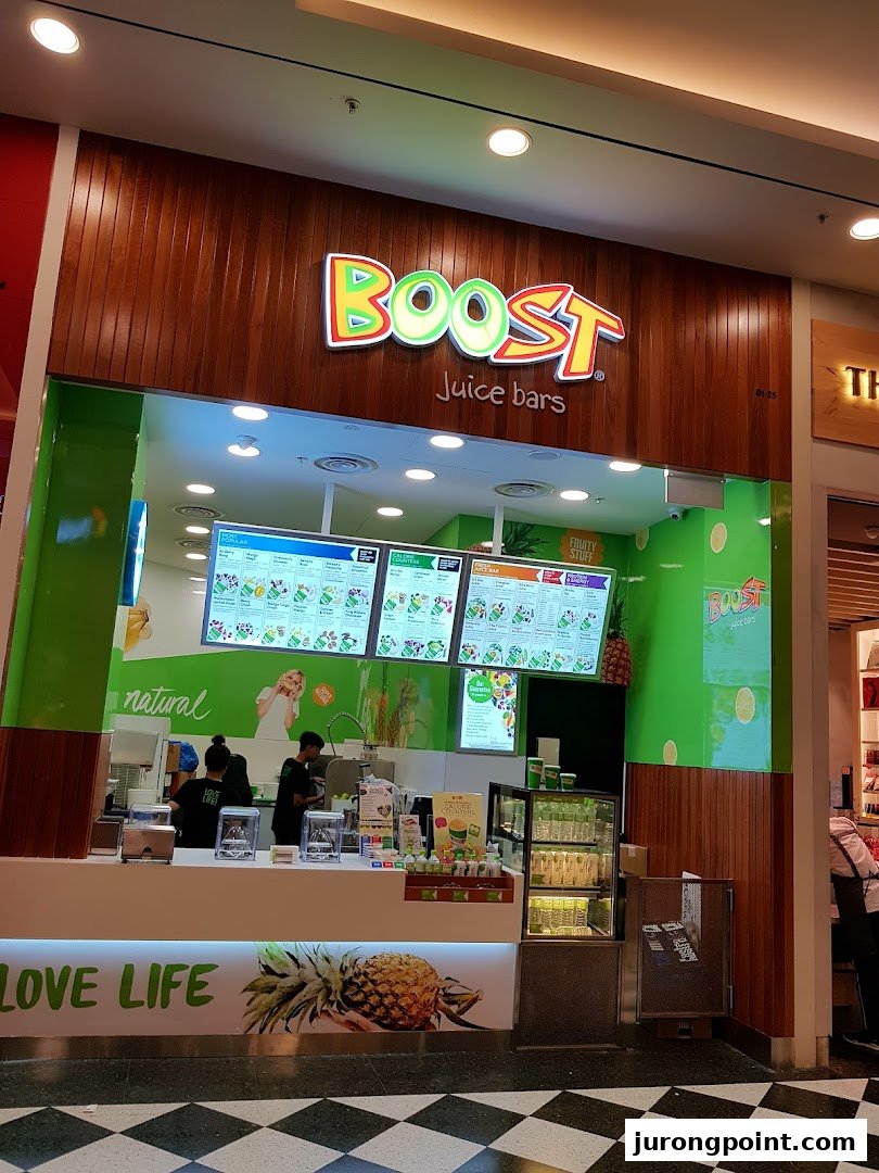 The vibrant green and wood exterior of a Boost Juice bar with its prominent logo and digital menus.