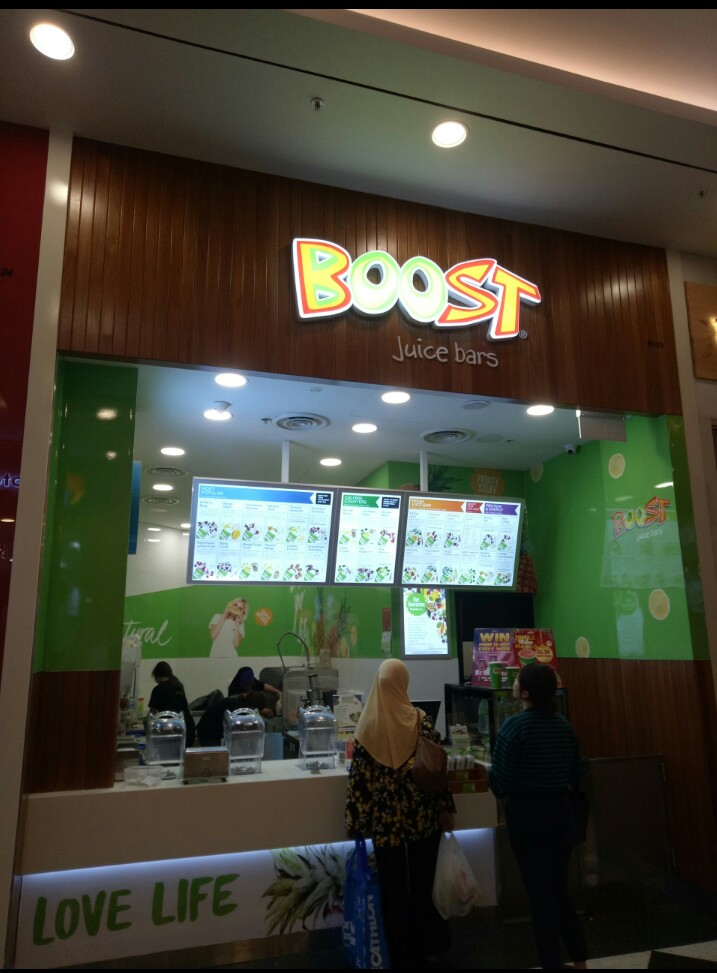A vibrant Boost Juice bar with customers at the counter and clear menu displays.