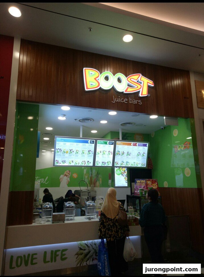 A vibrant Boost Juice bar with customers at the counter and clear menu displays.