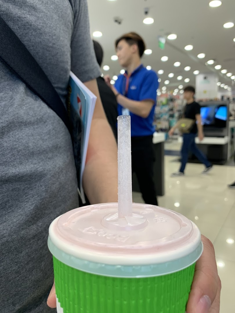 A person holds a refreshing Boost Juice drink with a straw in a retail setting.