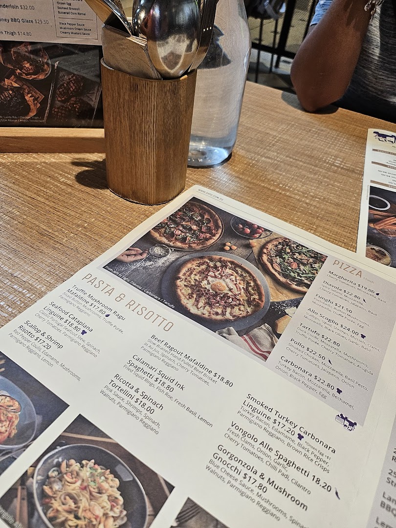 A close-up view of a restaurant menu displaying pasta, risotto, and pizza dishes with prices.