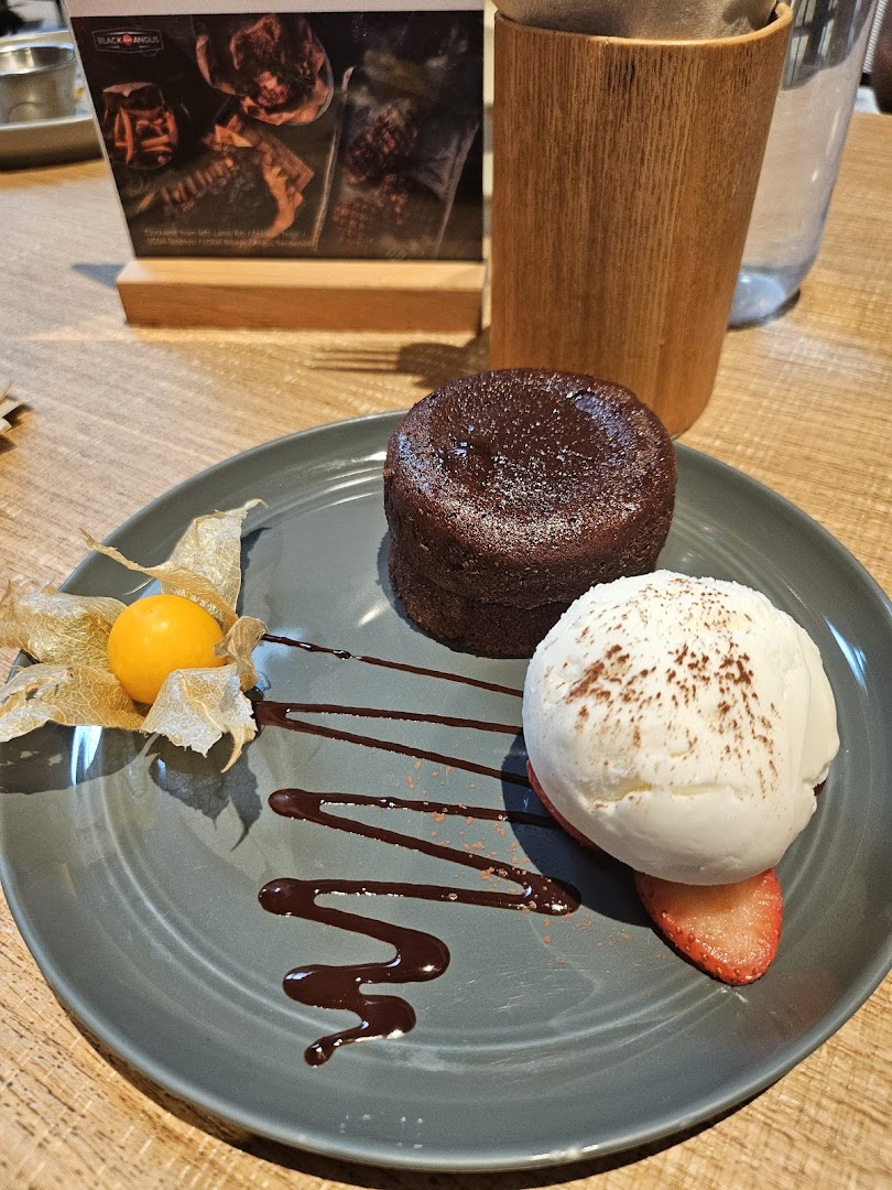 A delectable chocolate lava cake with vanilla ice cream, strawberry, and physalis on a plate.