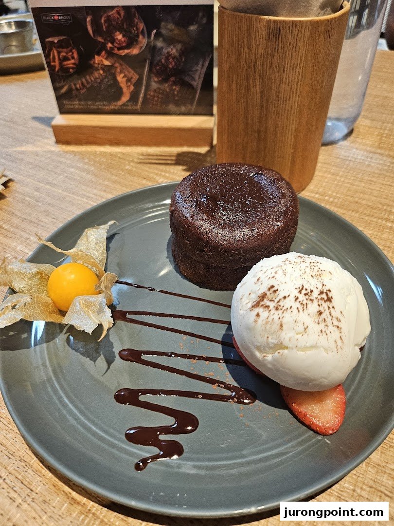 A delectable chocolate lava cake with vanilla ice cream, strawberry, and physalis on a plate.
