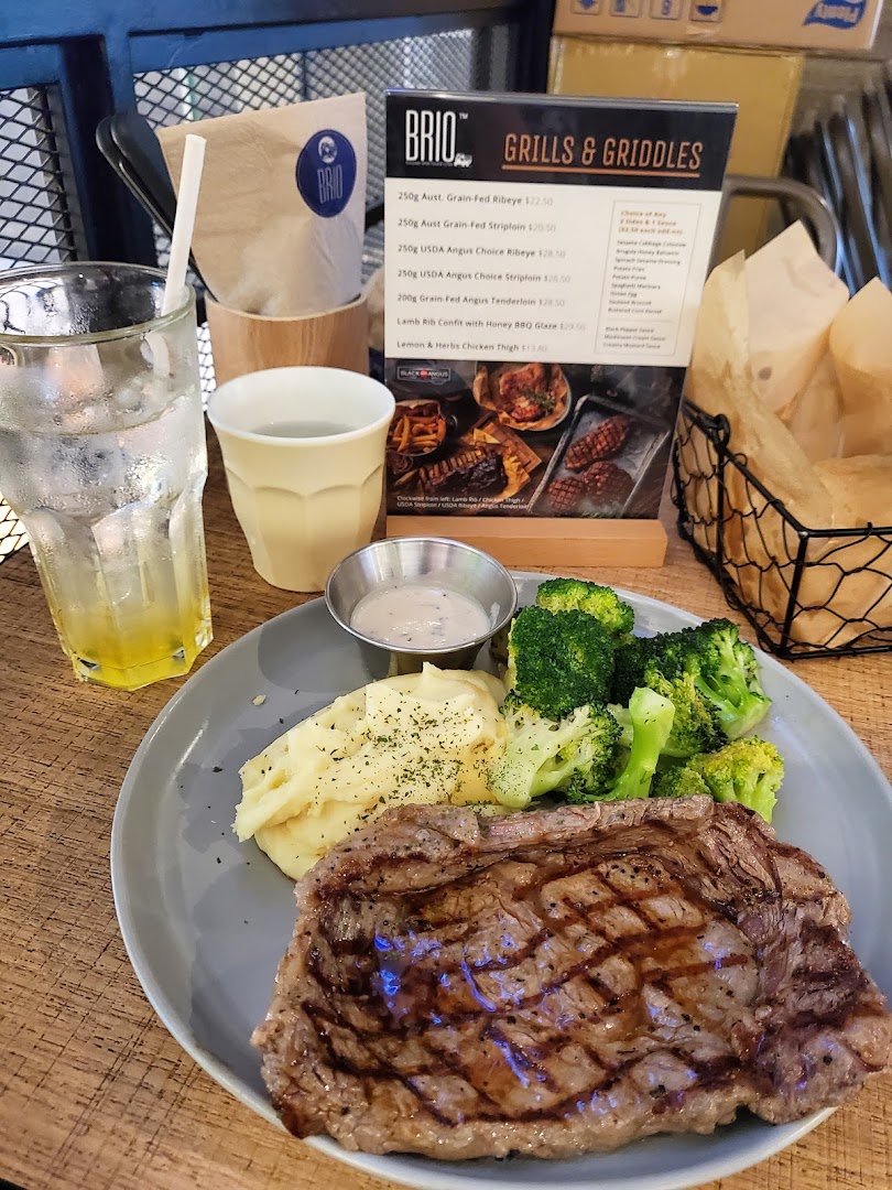 A grilled steak meal with mashed potatoes and broccoli, next to a Brio menu.