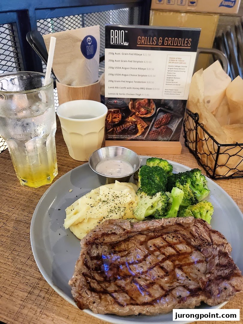 A grilled steak meal with mashed potatoes and broccoli, next to a Brio menu.