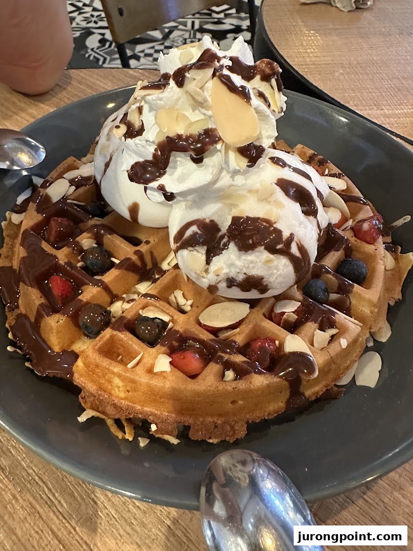 A delicious waffle topped with whipped cream, chocolate drizzle, fresh berries, and sliced almonds.