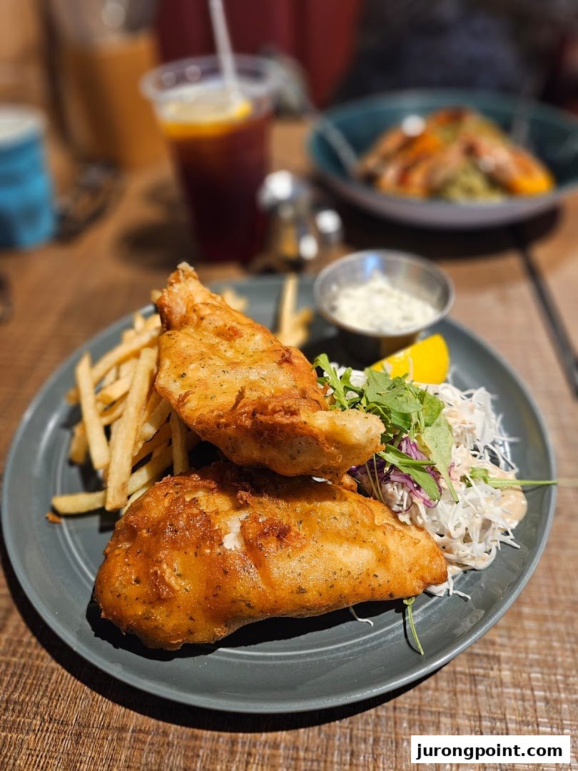 A plate of golden-fried fish and chips with coleslaw, tartar sauce, and a drink at Brio.